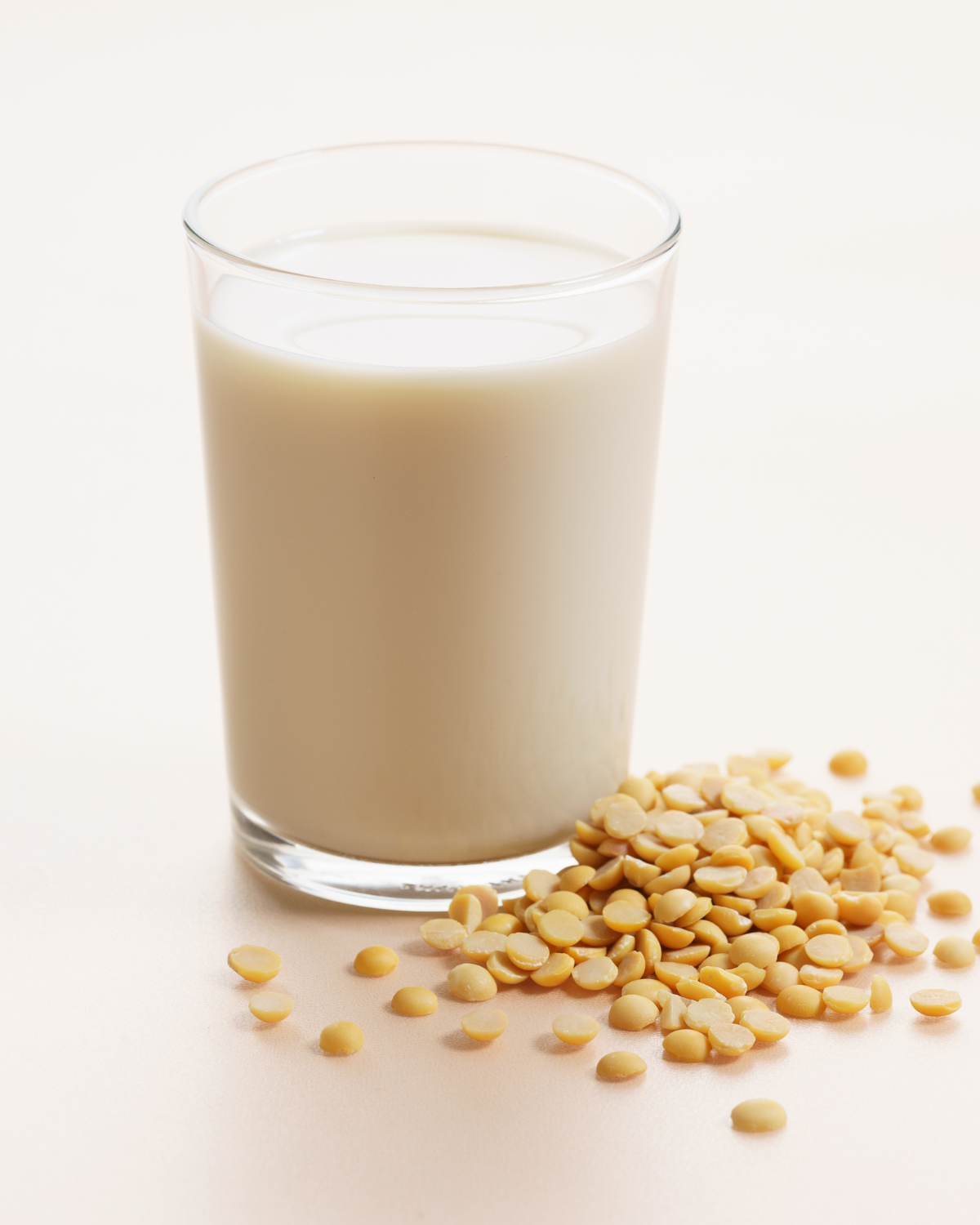 soy milk vs almond milk – glass of creamy soy milk with soybeans